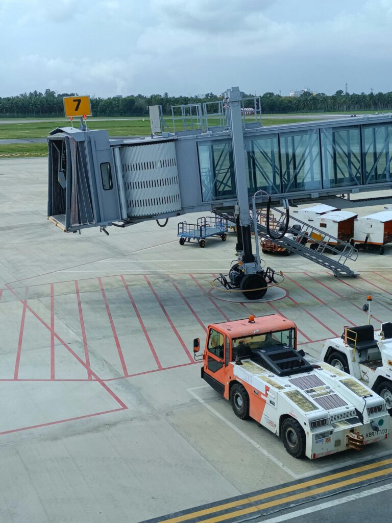Empty jet bridge and service vehicle on airport runway during day.